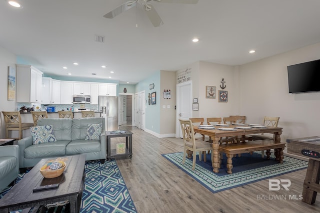 living room featuring a ceiling fan, visible vents, light wood-style floors, and recessed lighting
