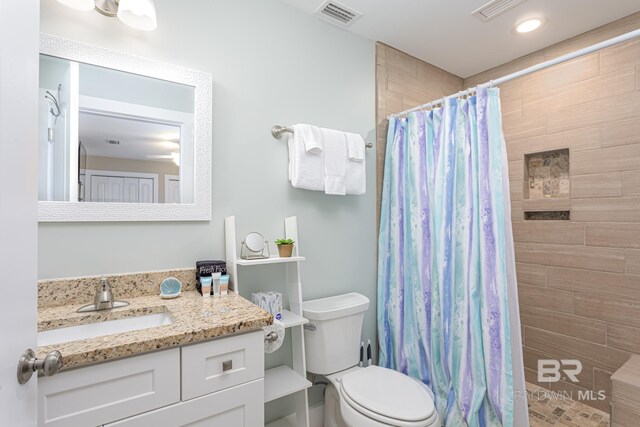 full bathroom with vanity, visible vents, toilet, and tiled shower
