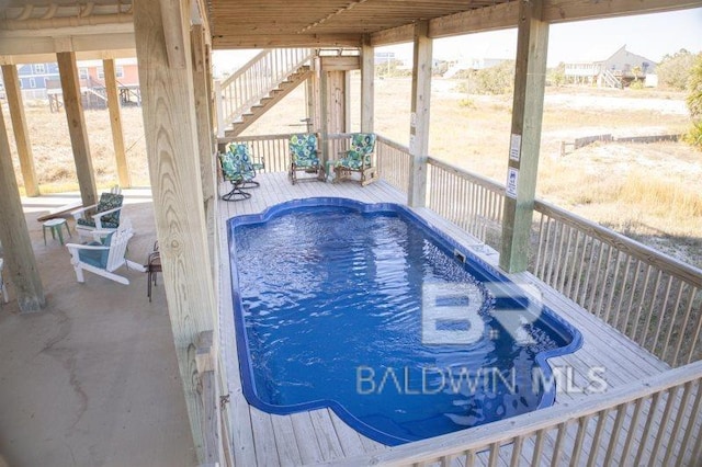 view of pool with a hot tub and stairs