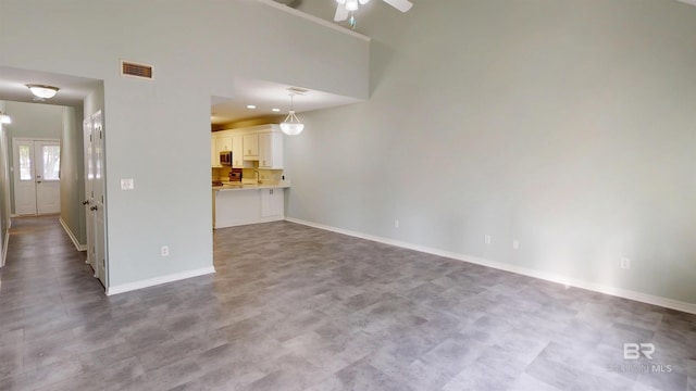 unfurnished living room with baseboards, ceiling fan, and visible vents