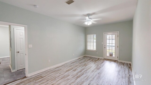 spare room featuring light wood-style floors, baseboards, a ceiling fan, and visible vents