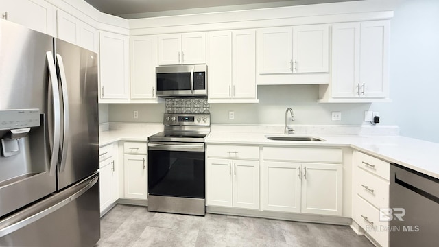 kitchen featuring a sink, light countertops, stainless steel appliances, and white cabinetry