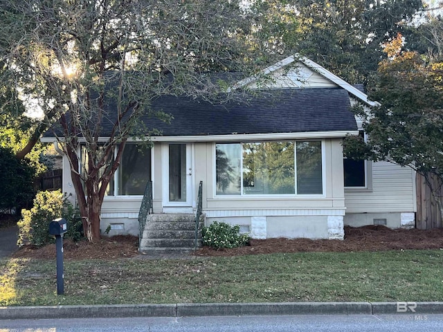 view of front facade with crawl space, a front lawn, entry steps, and roof with shingles