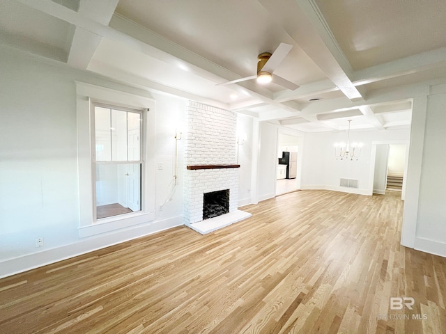 unfurnished living room featuring a brick fireplace, light hardwood / wood-style flooring, beamed ceiling, ceiling fan with notable chandelier, and coffered ceiling