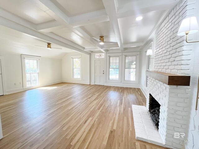 unfurnished living room featuring light wood finished floors, a wealth of natural light, beam ceiling, ceiling fan, and a fireplace