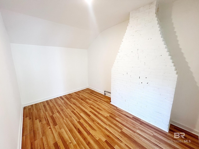 bonus room with vaulted ceiling, baseboards, and light wood-style flooring
