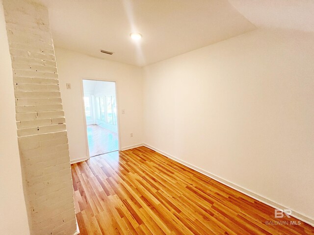 empty room with light wood-type flooring, visible vents, and baseboards