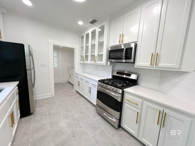 kitchen featuring decorative backsplash, glass insert cabinets, stainless steel appliances, white cabinetry, and visible vents