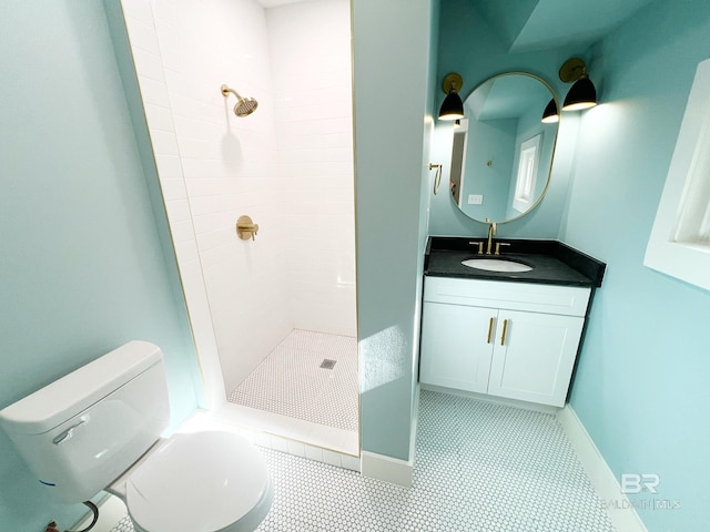 bathroom with toilet, vanity, tile patterned flooring, and a tile shower