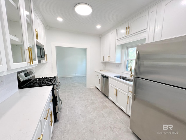 kitchen with white cabinets, light countertops, a sink, glass insert cabinets, and appliances with stainless steel finishes