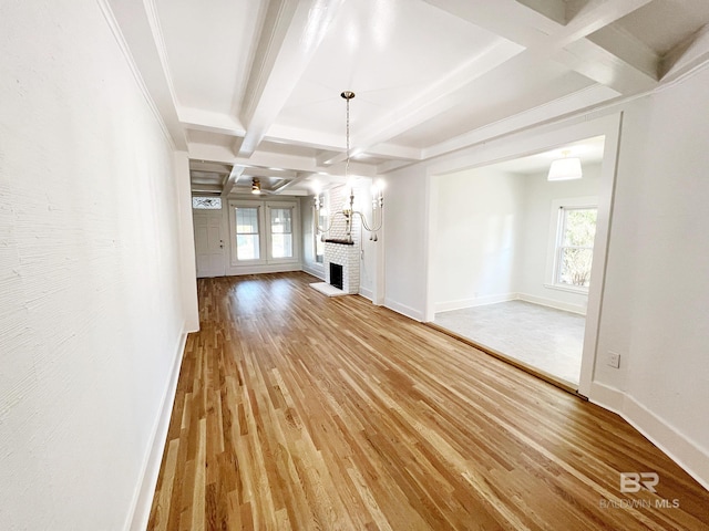 unfurnished living room with hardwood / wood-style floors, ornamental molding, beamed ceiling, a fireplace, and coffered ceiling