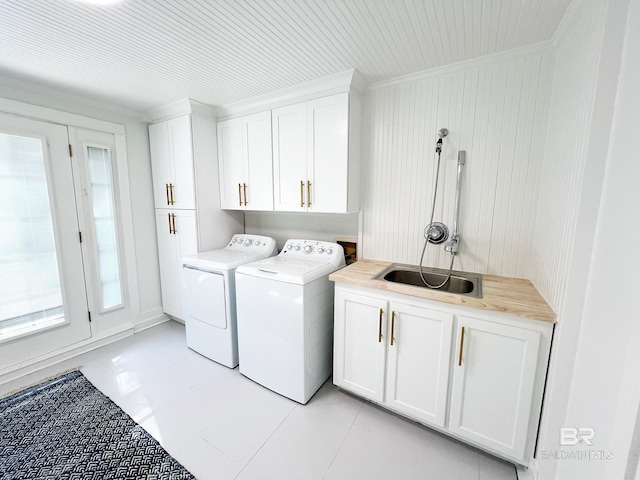 clothes washing area featuring washing machine and clothes dryer, a sink, ornamental molding, cabinet space, and light tile patterned floors