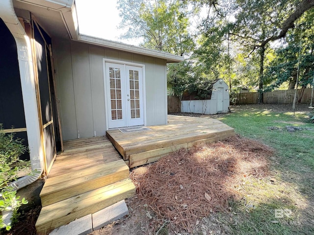 deck featuring a fenced backyard, a yard, a shed, an outdoor structure, and french doors