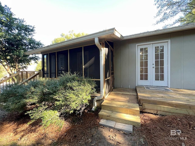 back of property featuring a wooden deck, a sunroom, and french doors