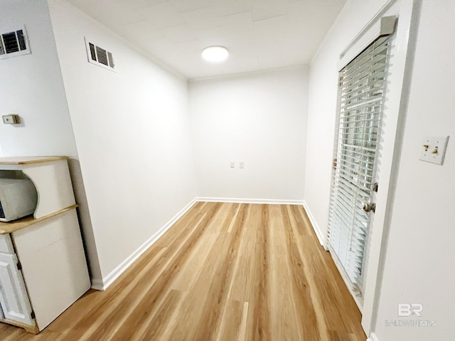 interior space with baseboards, light wood-style flooring, and visible vents