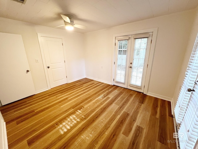 spare room with baseboards, french doors, wood finished floors, and a ceiling fan