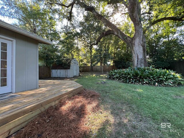 view of yard with a storage unit, an outbuilding, a fenced backyard, and a deck