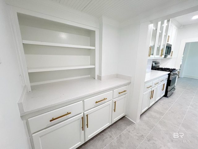interior space featuring white cabinets, glass insert cabinets, open shelves, light countertops, and appliances with stainless steel finishes