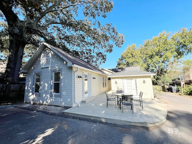 back of property featuring outdoor dining space, fence, and a deck