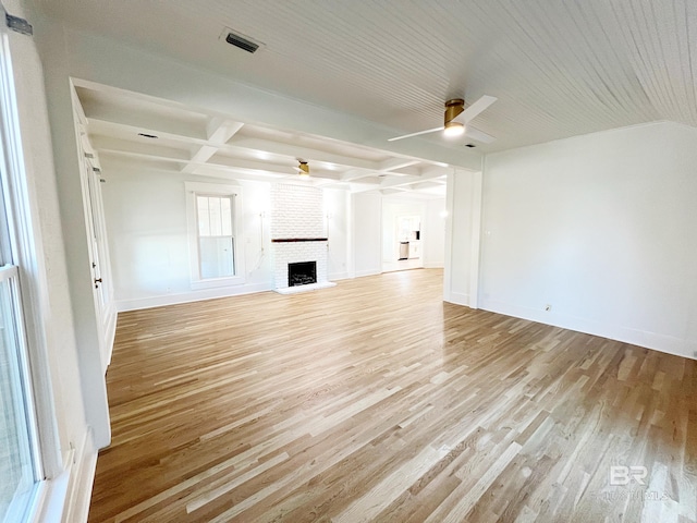 unfurnished living room with light hardwood / wood-style floors, beamed ceiling, a fireplace, and ceiling fan