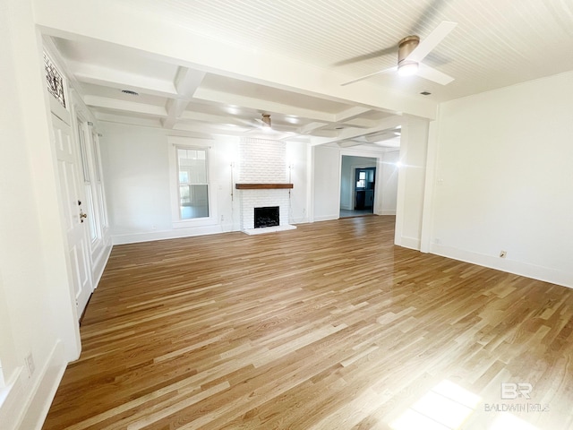 unfurnished living room featuring coffered ceiling, beamed ceiling, light wood-style floors, a brick fireplace, and ceiling fan