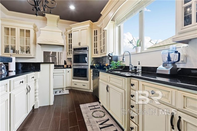 kitchen with sink, crown molding, premium range hood, appliances with stainless steel finishes, and cream cabinets