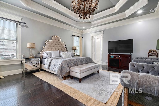 bedroom featuring ornamental molding, dark wood-type flooring, an inviting chandelier, and a tray ceiling