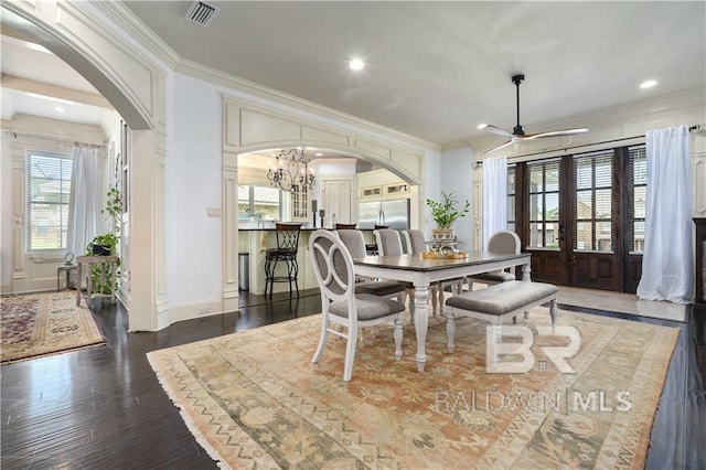 dining area featuring crown molding, dark wood-type flooring, ceiling fan with notable chandelier, and french doors