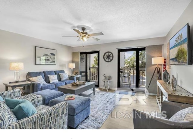 living room featuring a textured ceiling, wood finished floors, a ceiling fan, and baseboards