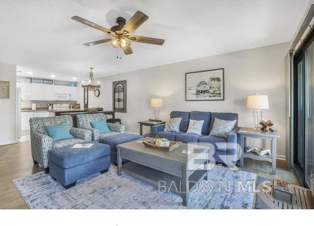 living room featuring recessed lighting, baseboards, wood finished floors, and ceiling fan with notable chandelier