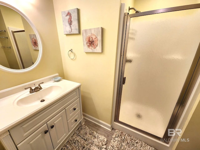 bathroom with hardwood / wood-style flooring, a shower with shower door, and vanity