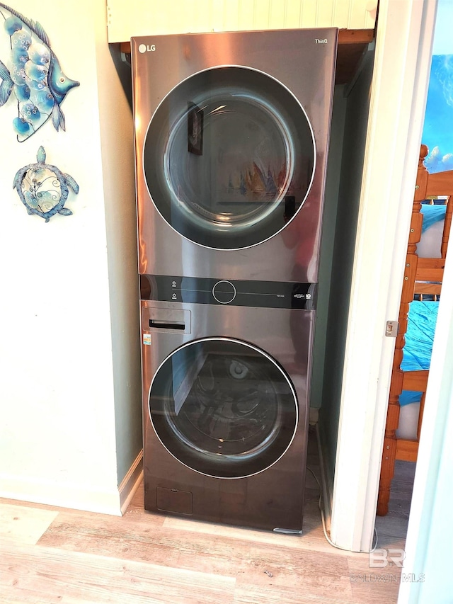 laundry room featuring light hardwood / wood-style flooring and stacked washer and dryer