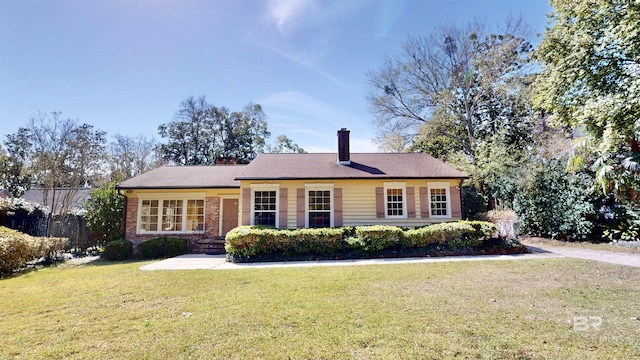 single story home featuring brick siding, a chimney, and a front yard