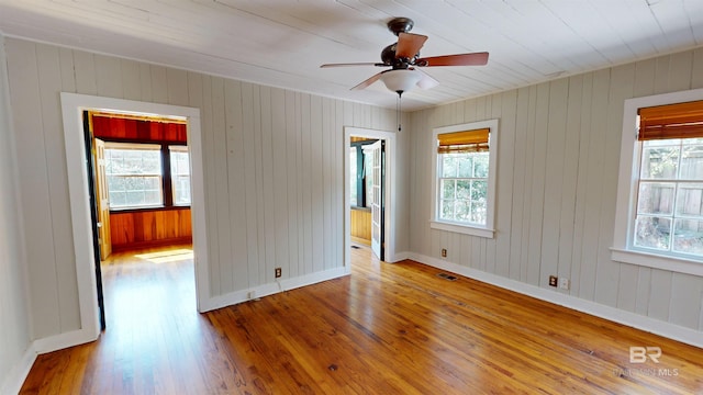 empty room featuring a wealth of natural light, visible vents, and hardwood / wood-style flooring