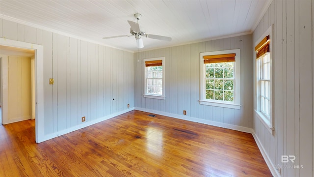 spare room featuring visible vents, crown molding, baseboards, wood finished floors, and a ceiling fan