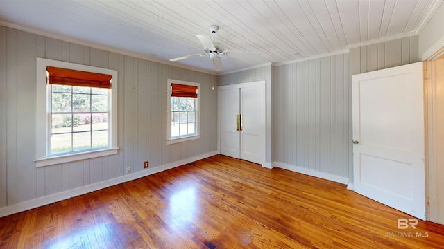 spare room featuring ceiling fan, baseboards, wood finished floors, and ornamental molding