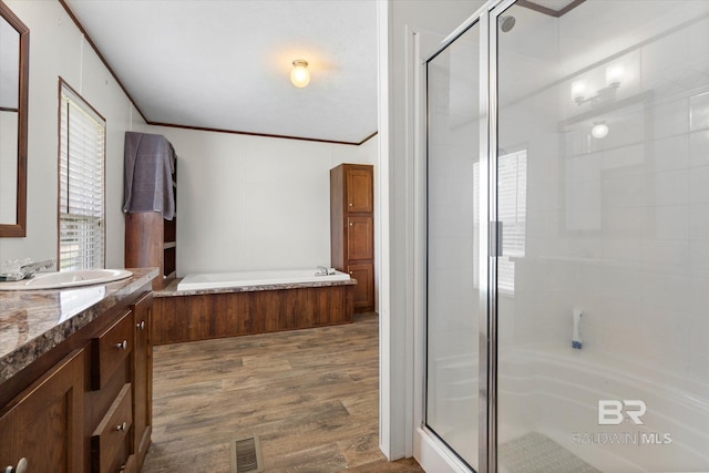 19300 Community Ln, Summerdale, AL 36580 - bathroom featuring vanity, a stall shower, a garden tub, ornamental molding, and wood finished floors