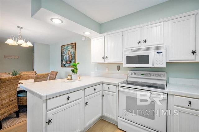 kitchen featuring tile countertops, hanging light fixtures, white cabinets, white appliances, and a peninsula