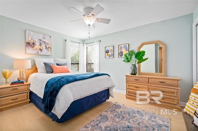 bedroom featuring light wood finished floors, a ceiling fan, and baseboards