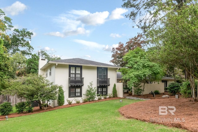 6000 Shenandoah Rd, Mobile, AL 36608 - view of front of house with a front yard, stucco siding, a chimney, and a balcony