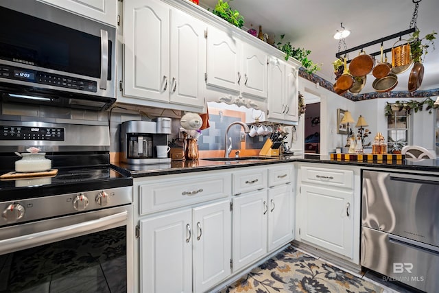 kitchen with white cabinets, appliances with stainless steel finishes, tasteful backsplash, and sink