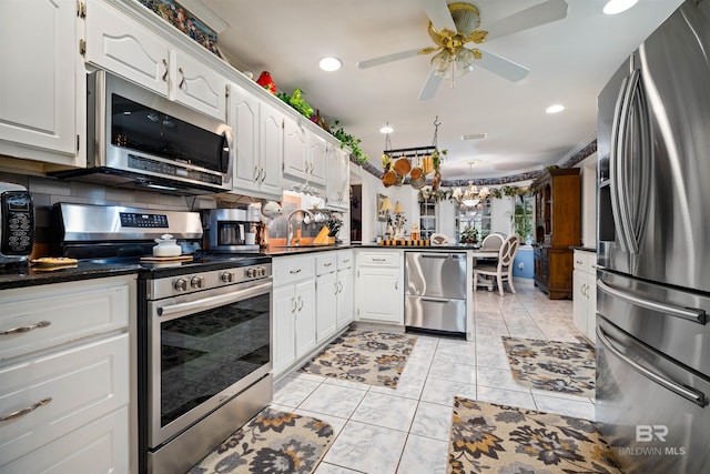 kitchen with appliances with stainless steel finishes, white cabinetry, decorative backsplash, and kitchen peninsula