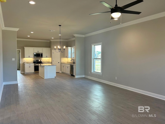 kitchen with appliances with stainless steel finishes, sink, a center island, white cabinets, and hanging light fixtures