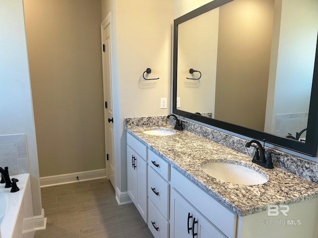 bathroom with vanity, a washtub, and wood-type flooring