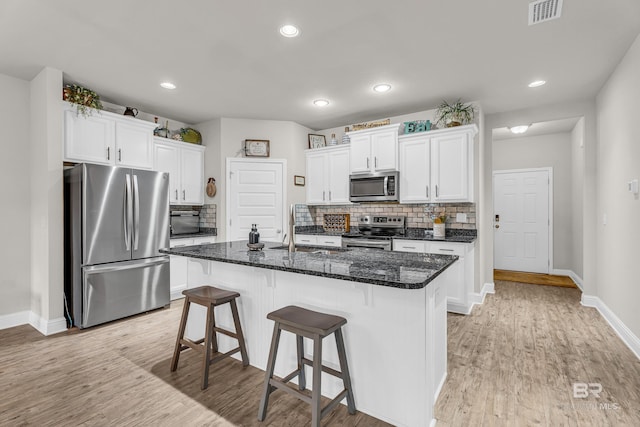 1556 Kairos Loop, Foley, AL 36535 - kitchen featuring stainless steel appliances, tasteful backsplash, white cabinets, a kitchen bar, and light wood-style floors