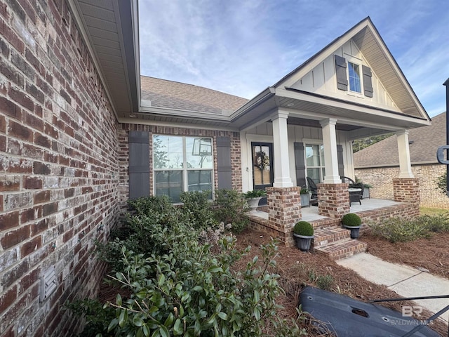 property entrance with board and batten siding, brick siding, and a porch