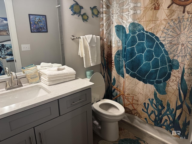 bathroom featuring toilet, a shower with shower curtain, and vanity