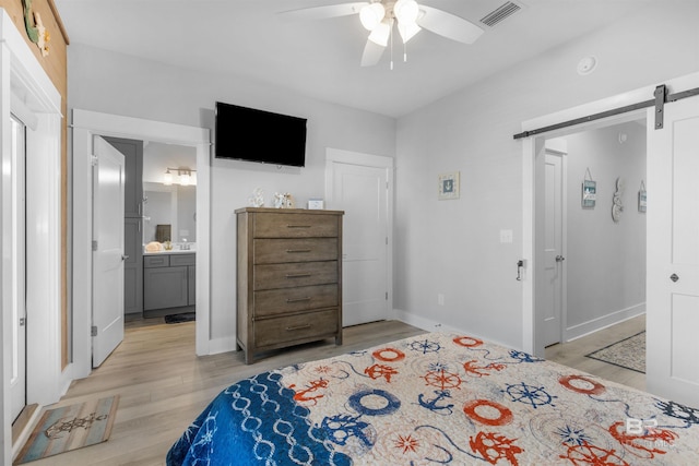 bedroom with visible vents, baseboards, a barn door, ceiling fan, and light wood-style floors