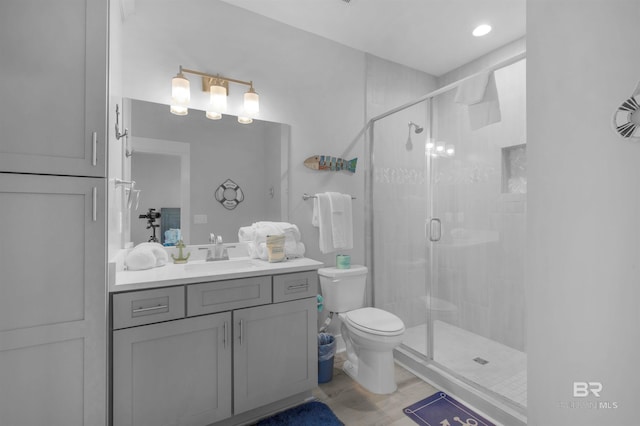 full bathroom featuring a shower stall, wood finished floors, vanity, and toilet