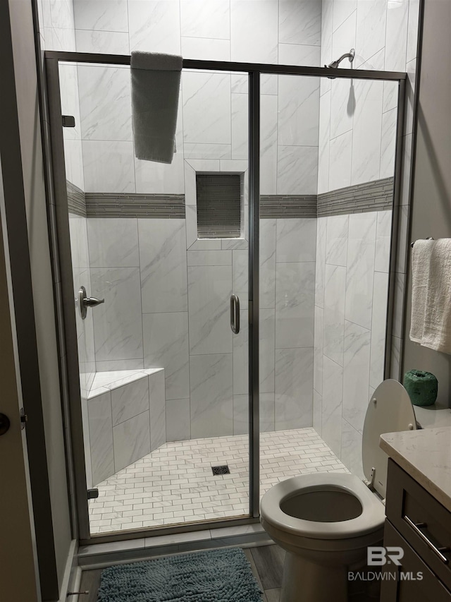 bathroom featuring toilet, a stall shower, and vanity